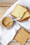 Peanut butter on white bread on wooden background. Flat lay