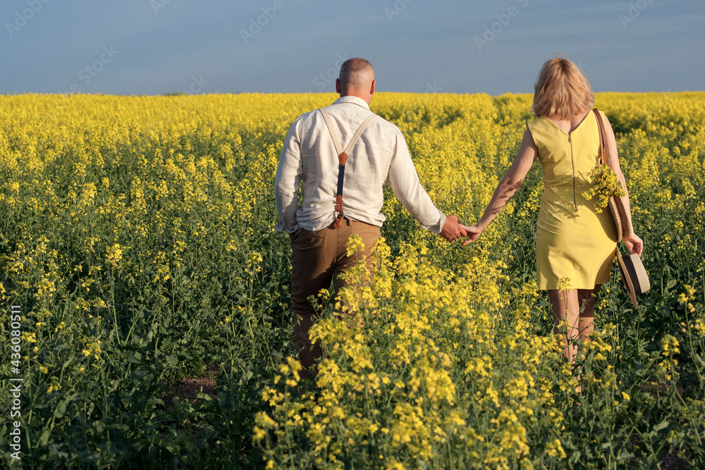 man and woman in yellow rapeseed field