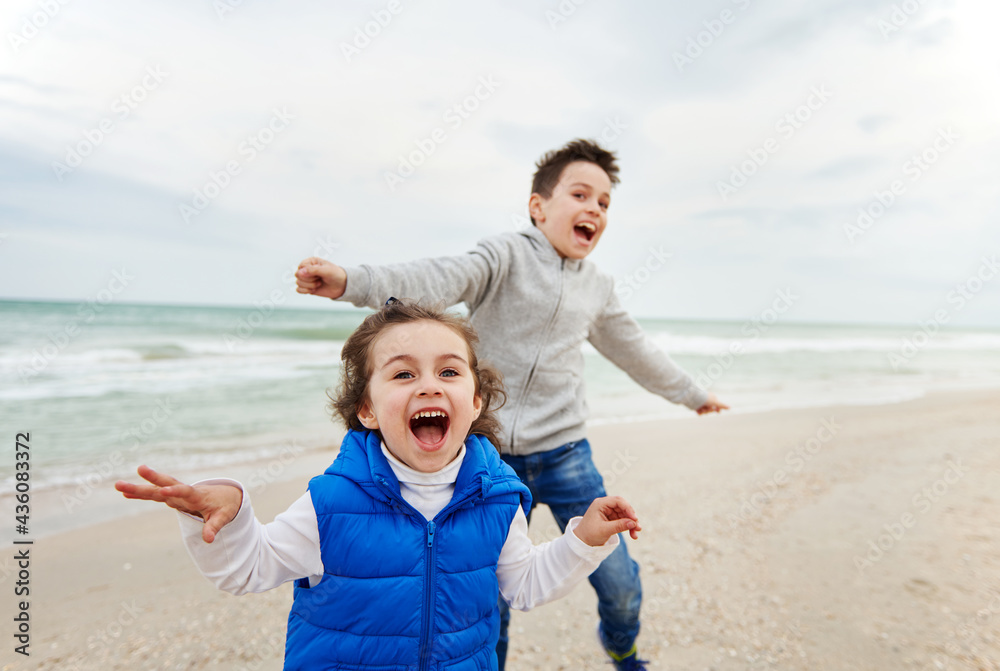 Adorable children, boy and girl, laughing and playing on the beach. Happy childhood concept. International Children's Day Adorable children, boy and girl, laughing and playing on the beach. Happy childhood concept. International Children's Day