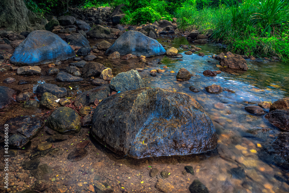 Fototapeta premium Water flowing through stones and down small rock steps natural scene.