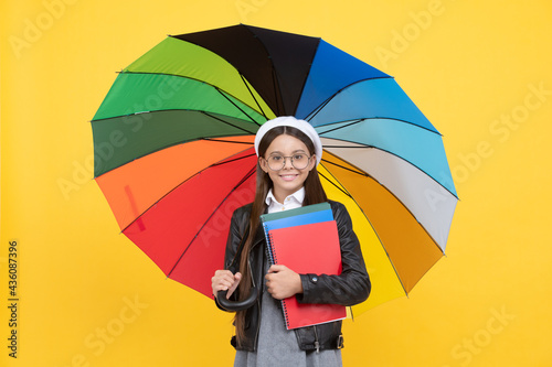 teen child under colorful parasol. kid in beret with rainbow umbrella. autumn season.