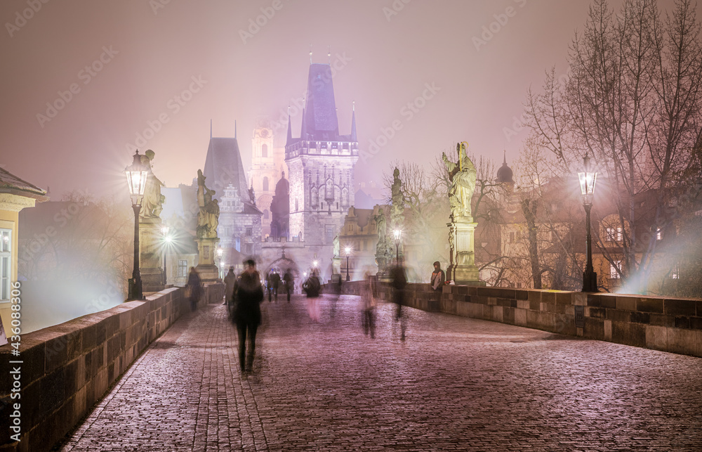 The beautiful romantic scene on the bridge at night with gothic architecture and people on the street in Prague