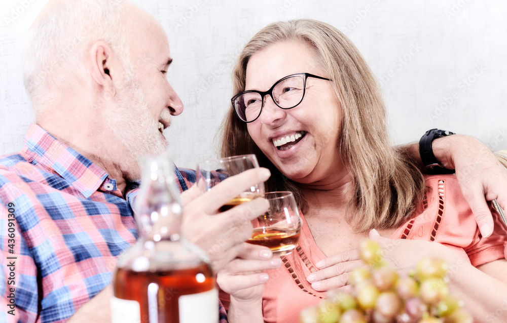 Cheerful senior couple tasting whiskey at home