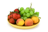 Fruits and berries are on a wooden plate. Apricots, strawberries and green grapes