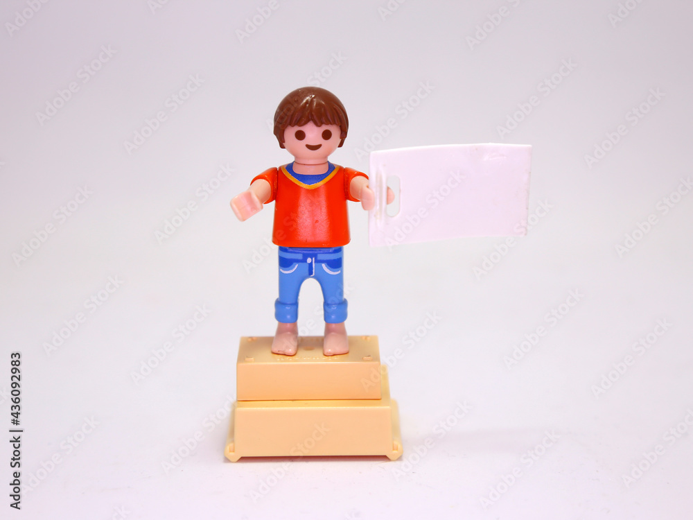 Playmobil doll. Child with blank banner. Boy on podium. Winner. Happy  child. Blond. Number one. White background. Isolated. Toy. Smiley face.  Modern clothing. Person. Human. Little boy. Stock Photo | Adobe Stock