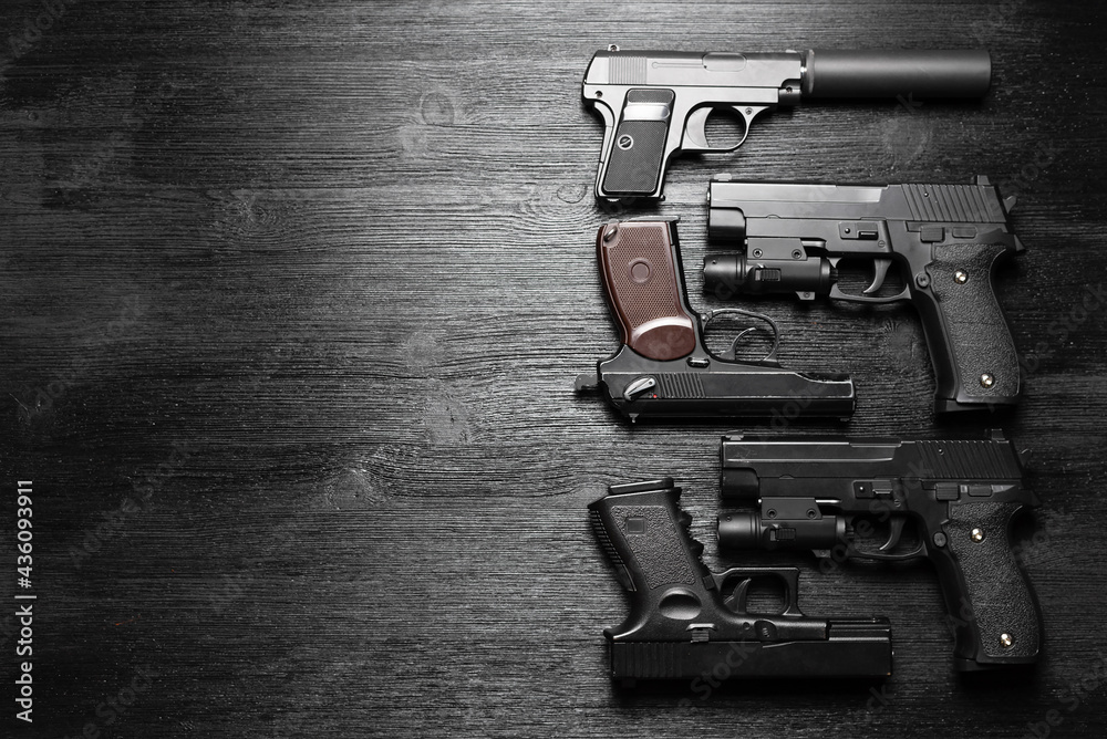 Airsoft guns on the black wooden table flat lay background with copy space.