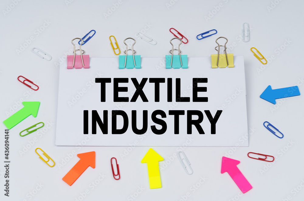On the table there are paper clips and directional arrows, a sign that says - Textile Industry On the table there are paper clips and directional arrows, a sign that says - Textile Industry