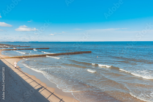 Zelenogradsk. Baltic sea embankment. Calm  calm sea  waves  breakwaters. A man in a jacket walks along the shore