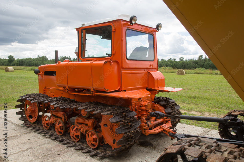 Old red tracked tractor standing near field Old red tracked tractor standing near field