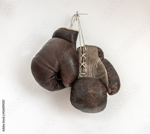 Old boxing gloves hanging on a white wall © milkovasa