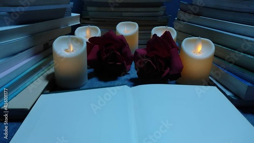 Blank white book pages, swaying candles, surrounded by red roses, giving thoughts, notes of knowledge.  There is a light in life, a sense of determination and success. 