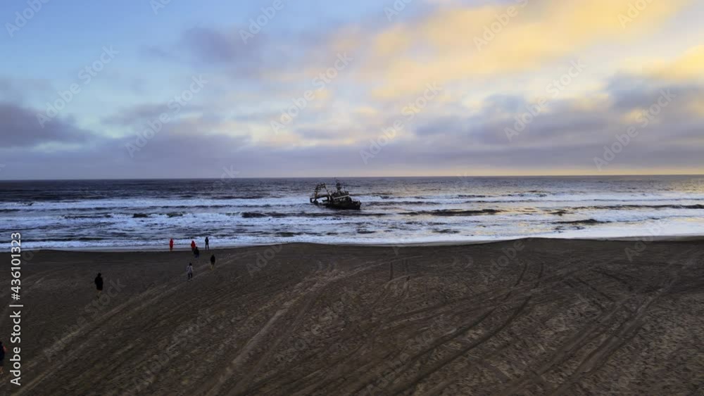 Drone shot revealing tourists standing on edge of beach near seashore. Expedition of travellers enjoying view of foam from seawaves meeting with shoreline. Fully equipped suv cars on sand shot by Drone shot revealing tourists standing on edge of beach near seashore. Expedition of travellers enjoying view of foam from seawaves meeting with shoreline. Fully equipped suv cars on sand shot by