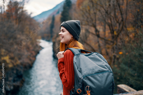 woman with backpack in forest autumn river nature landscape