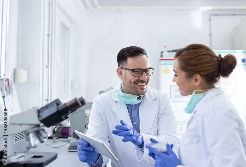 Two smiling doctors scientists discussing test results in laboratory Two smiling doctors scientists discussing test results in laboratory