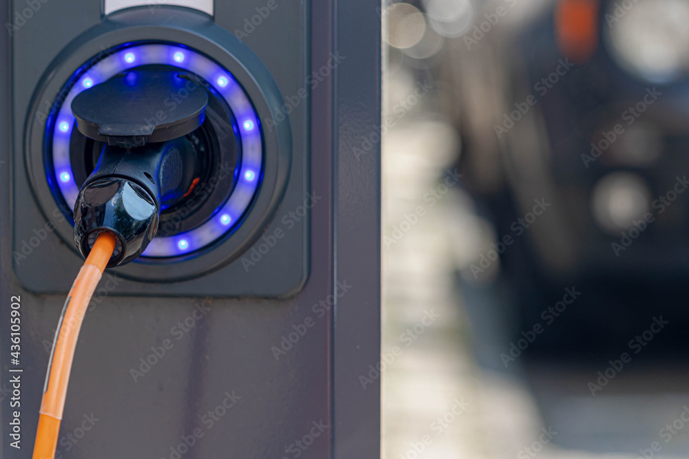 Close Up power supply connect to electric vehicle for charging battery, Charging an electric car in public station by the street along the canal, Green energy, Amsterdam, Netherlands. Close Up power supply connect to electric vehicle for charging battery, Charging an electric car in public station by the street along the canal, Green energy, Amsterdam, Netherlands.