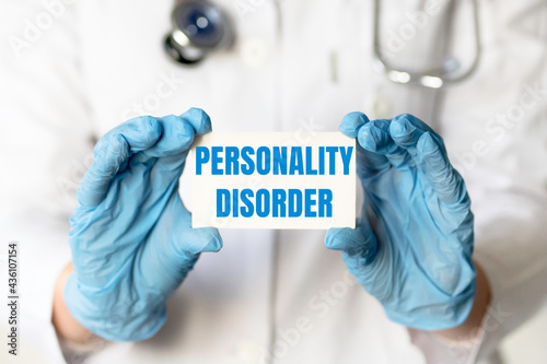 A medical worker in gloves holds a card with the words PERSONALITY DISORDER. Medical concept.