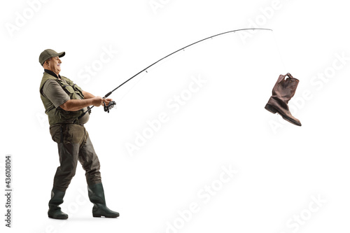 Full length profile shot of a mature fisherman catching an old boot with a fishing rod