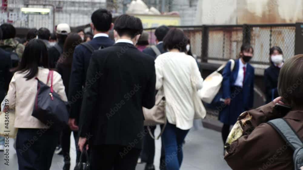 OSAKA, JAPAN - APRIL 2021 : Back shot and unidentified crowd of people wearing surgical masks to protect from Coronavirus (COVID-19) at the street. Slow motion shot. In front focus. OSAKA, JAPAN - APRIL 2021 : Back shot and unidentified crowd of people wearing surgical masks to protect from Coronavirus (COVID-19) at the street. Slow motion shot. In front focus.