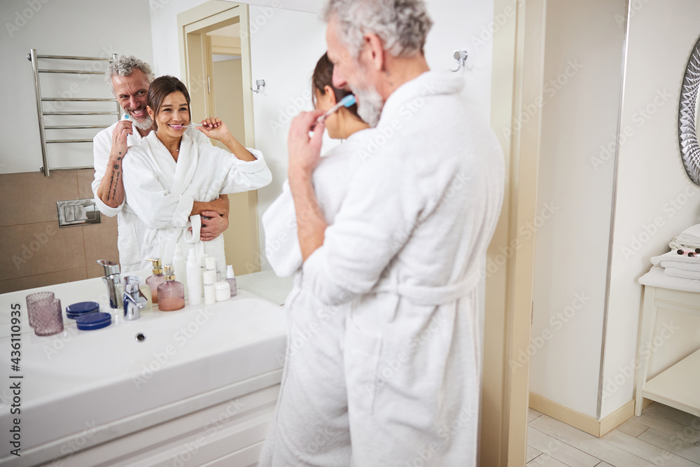 Romantic affectionate beautiful woman and man standing in front of the mirror in room indoors Romantic affectionate beautiful woman and man standing in front of the mirror in room indoors