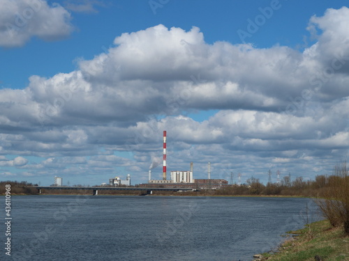 White clouds on blue sky and red striped chimney