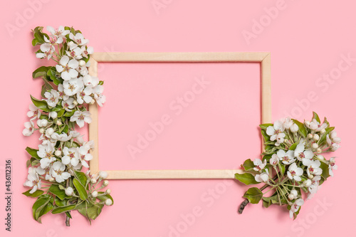 Creative layout with blossoming pear branches and photo frame on pastel pink background. Spring minimal concept. Flat lay, copy space, top view