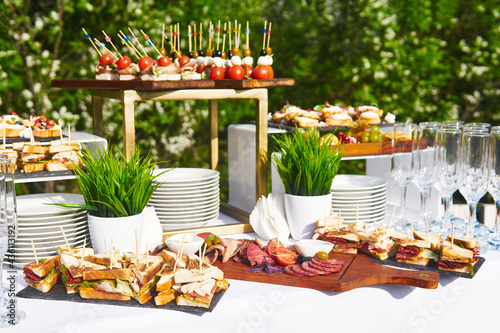 Картината върху платно open-air buffet table, glasses and sandwiches on skewers before the start of the