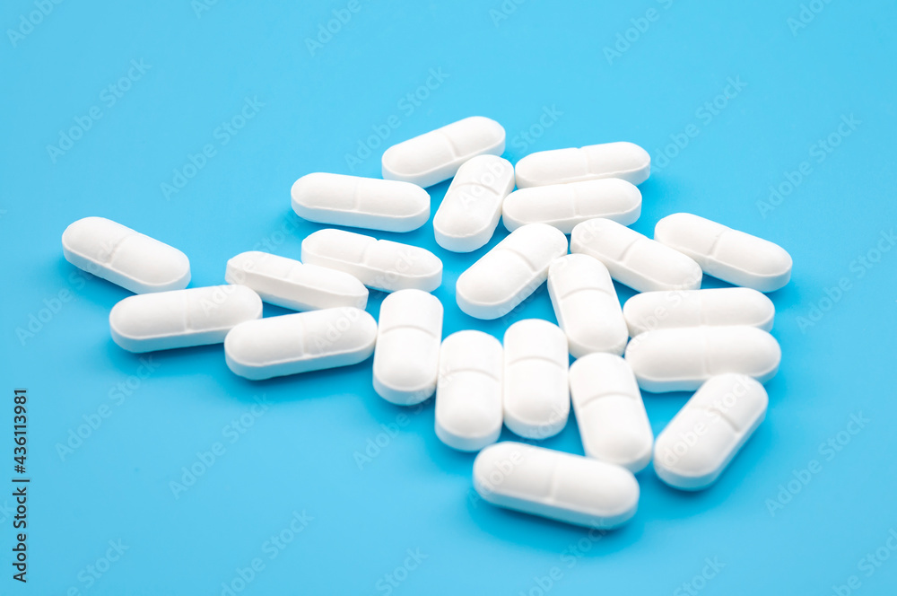 Prescription medication, pharmaceutical treatment and pain management concept with white pills isolated on blue background