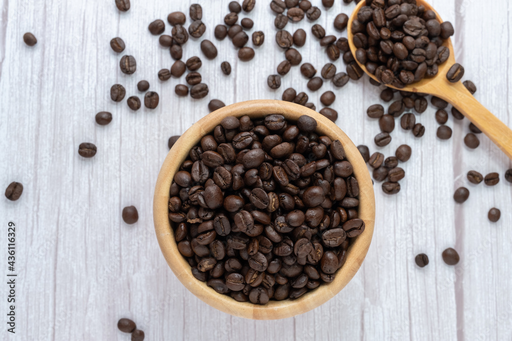 Coffee beans in wooden cup and spoon on wooden floor background. Coffee beans in wooden cup and spoon on wooden floor background.