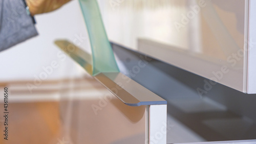 Obraz na płótnie CLOSE UP: Unrecognizable woman peels away plastic foil off a brand new dresser