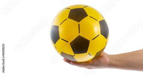 Young man s hand holding a yellow and black ball. Space for text.