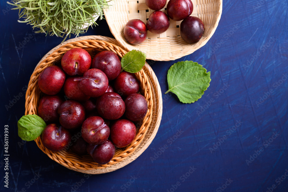 Fresh Japanese or Chinese plum fruit in bamboo basket on blue background, Top view Fresh Japanese or Chinese plum fruit in bamboo basket on blue background, Top view