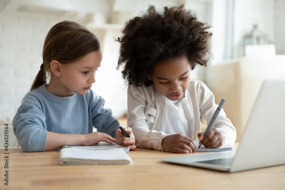 Smart small diverse sisters children write note study online on computer at home on quarantine. Little multiethnic girls kids prepare homework learn with laptop together. Distant education concept. Smart small diverse sisters children write note study online on computer at home on quarantine. Little multiethnic girls kids prepare homework learn with laptop together. Distant education concept.