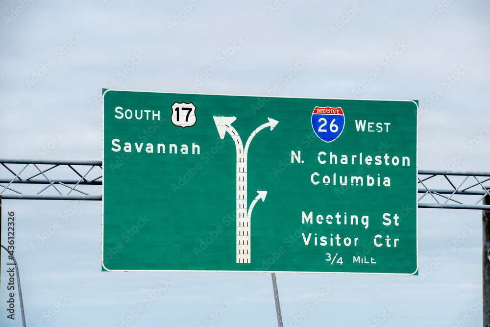 An overhead highway sign on the Ravenel bridge with directions to Savannah, North Charleston, Meeting Street and a visitor center
