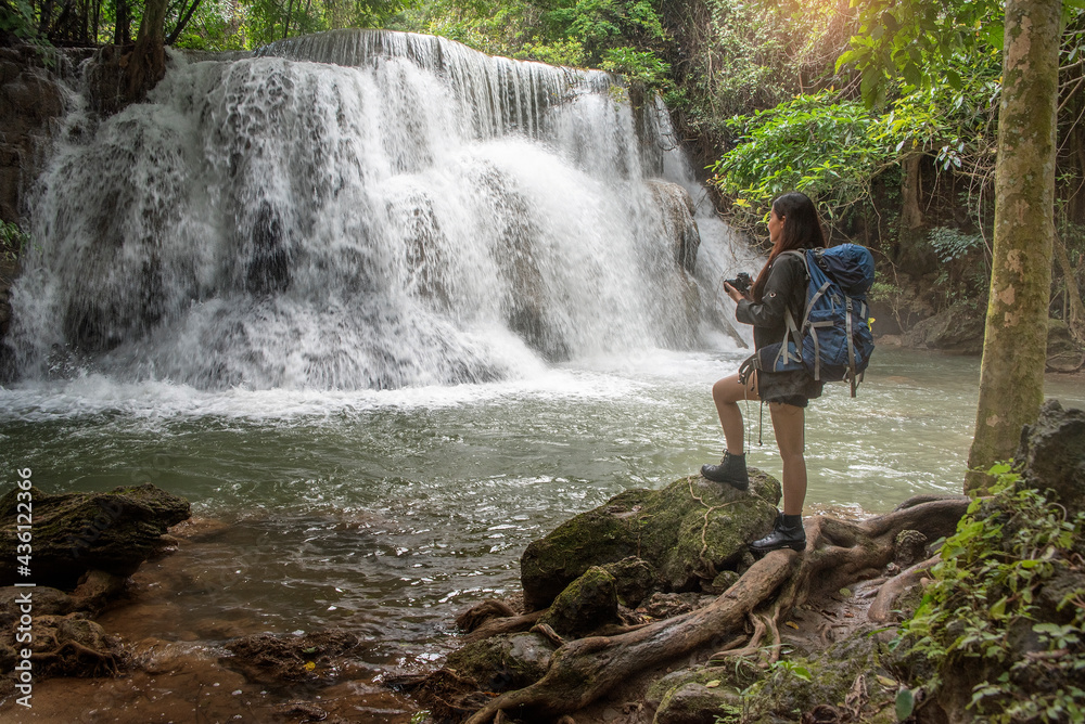 Asian female backpacker treks through the mountains to a waterfall
