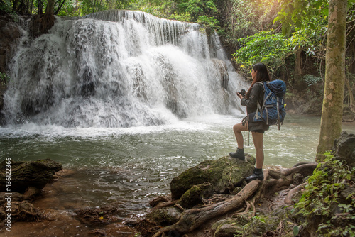 Obraz na płótnie Asian female backpacker treks through the mountains to a waterfall w salonie