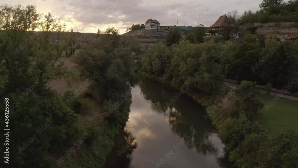 Aerial Moving Forward Along A Rural Village River At Dusk And Over A Hilltop Home, With Pastures, Trees, Homes, And A Warm Setting Sun - Naumburg, Germany Aerial Moving Forward Along A Rural Village River At Dusk And Over A Hilltop Home, With Pastures, Trees, Homes, And A Warm Setting Sun - Naumburg, Germany