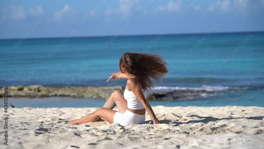 Young flexible fit woman dancing on the beach with sand in slow motion. Freedom, Individuality and originality concept Young flexible fit woman dancing on the beach with sand in slow motion. Freedom, Individuality and originality concept