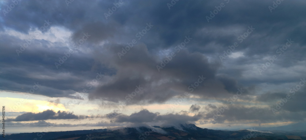 Fototapeta premium Le nuvole nel cielo al tramonto si posano sulle colline