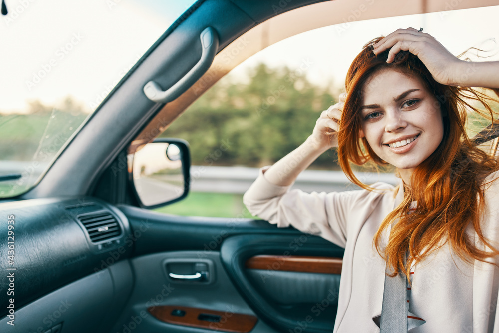 happy woman with red hair in front seat of car touching face with hands cropped view