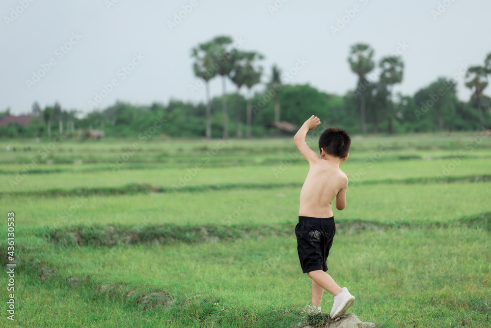 happy little Asian boy run on the field happy little Asian boy run on the field