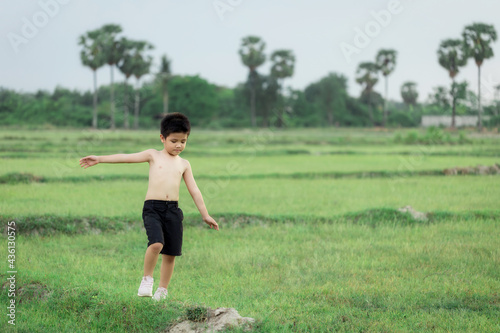 happy little Asian boy run on the field
