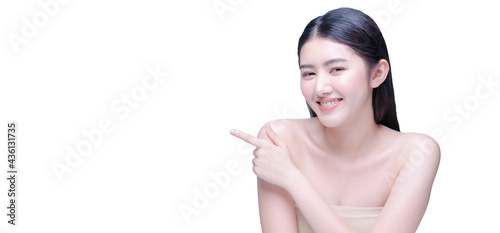 Beautiful young woman with healthy clean skin presenting something on her hand. Isolated on white. asian beauty smile and point finger on empty wall with copy space for label text and advertisment.