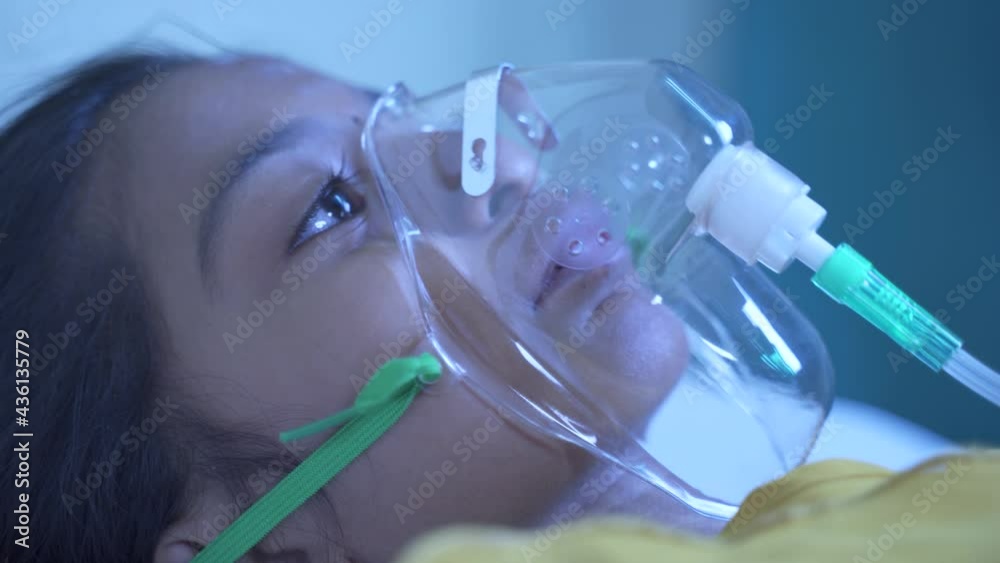 Close up shot of little girl kid breathing on ventilator oxygen mask at