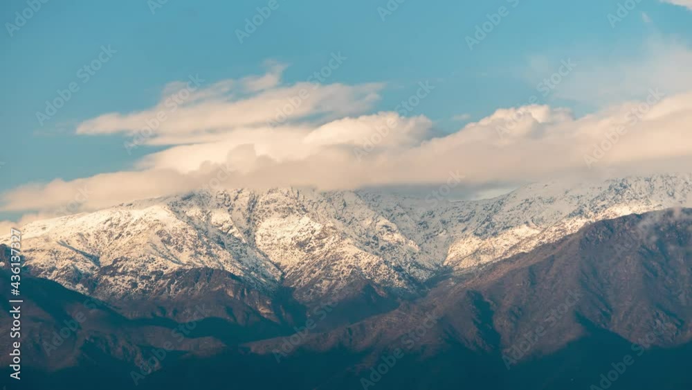 Timelapse of the Santiago de Chile Andean mountain range covered in snow with clouds touching the peak at sunset Timelapse of the Santiago de Chile Andean mountain range covered in snow with clouds touching the peak at sunset
