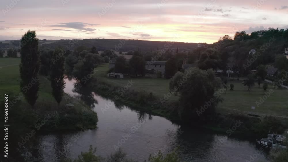 Aerial Moving Forward Along A Rural Village River At Dusk, With Pastures, Trees, Homes, And A Warm Setting Sun - Naumburg, Germany Aerial Moving Forward Along A Rural Village River At Dusk, With Pastures, Trees, Homes, And A Warm Setting Sun - Naumburg, Germany