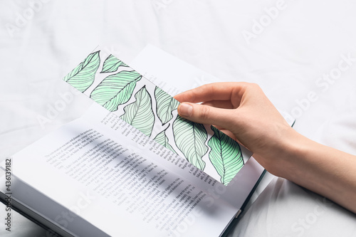 Woman with cute bookmark and book on bed photo
