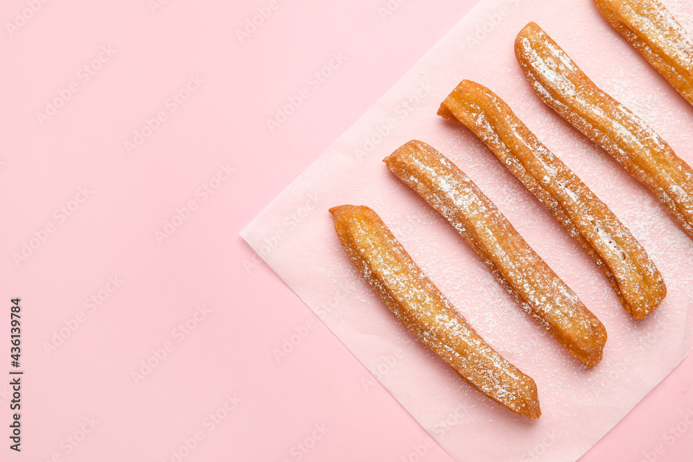 Parchment with tasty churros on color background Parchment with tasty churros on color background