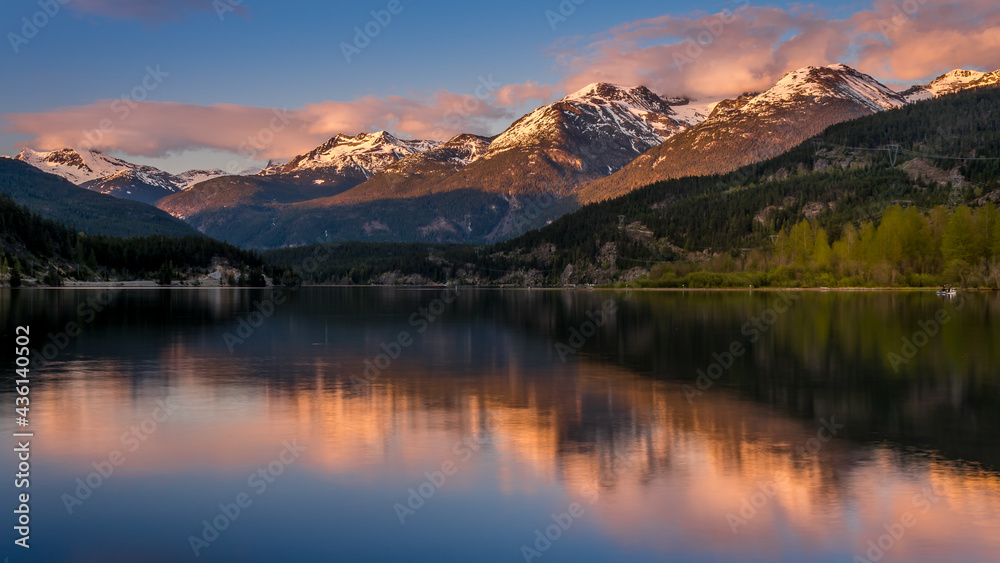 Sunset creating an Orange Sky over the Garibaldi Range and the Mountains Reflecting on the smooth surface of Green Lake near Whistler, British Columbia, Canada
