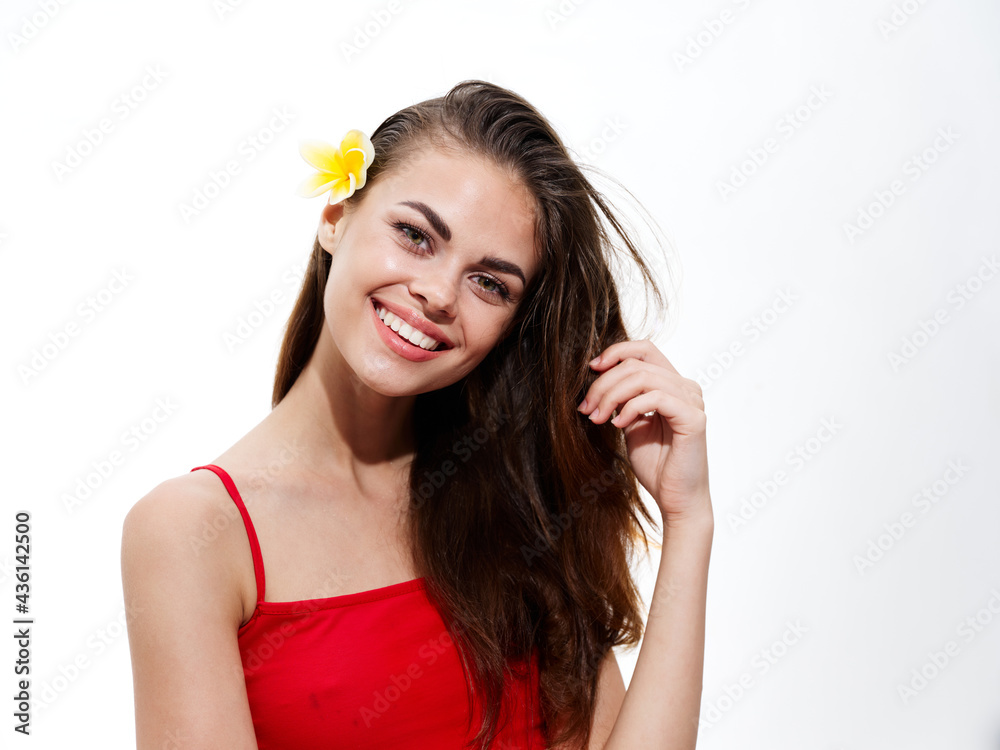 happy woman touching face with hand and yellow flower in hair red t-shirt happy woman touching face with hand and yellow flower in hair red t-shirt