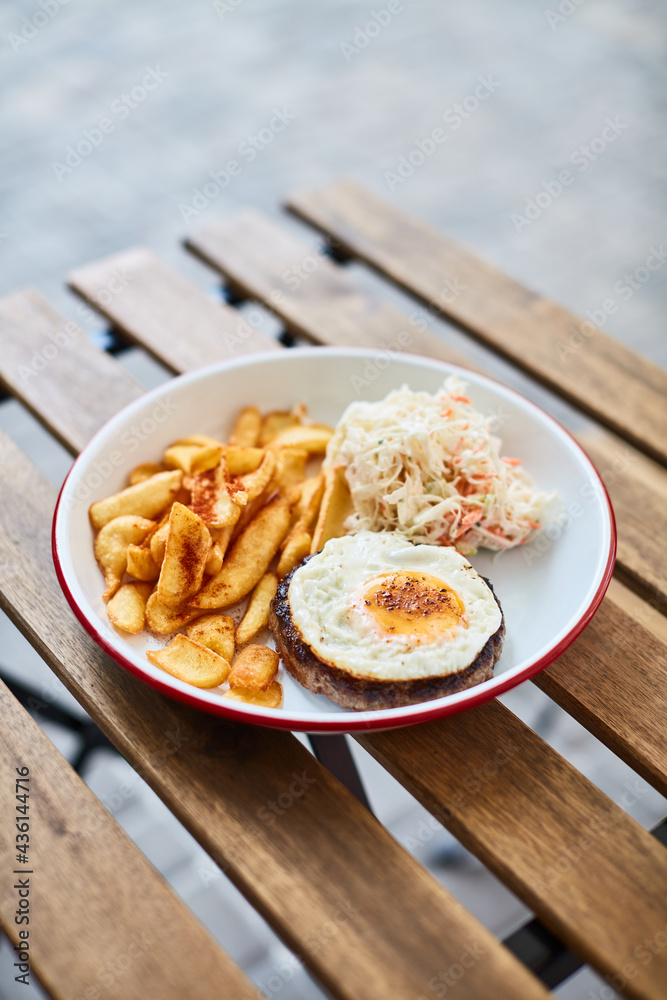 schnitzel with egg potatoes and cabbage on a wooden table on the street terrace summer schnitzel with egg potatoes and cabbage on a wooden table on the street terrace summer